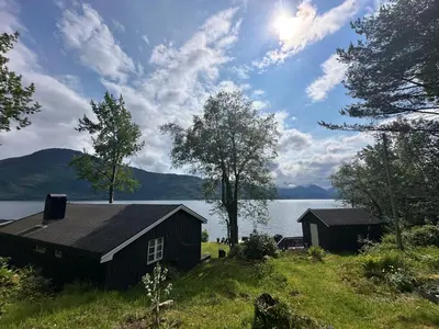 a house on a hill next to a body of water at Koselig hytte i sjøkanten in Ålesund