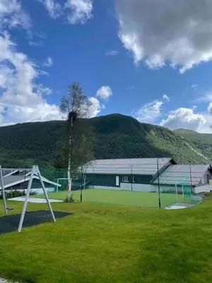 a building with a tennis court in a field at Familiy apartment in Myrkdalen Voss in Vossestrand