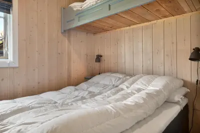 a large white bed in a room with wooden walls at Bitigrenda M in Beitostøl