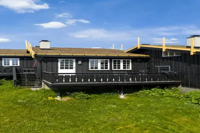 a black house with white windows and a green yard at Bitigrenda M in Beitostøl