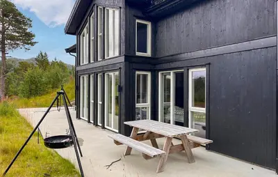 a black house with a picnic table and a grill at Cozy Home In Hovden I Setesdal - With Jacuzzi in Hovden