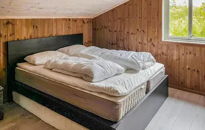 a large bed in a room with wooden walls at Cozy Home In Hovden I Setesdal - With Jacuzzi in Hovden