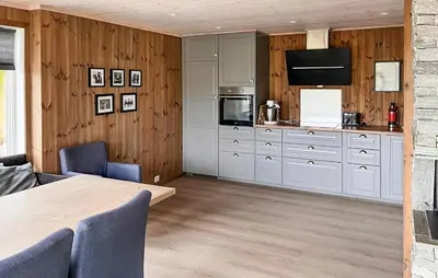 a kitchen with white cabinets and a wooden wall at Cozy Home In Hovden I Setesdal - With Jacuzzi in Hovden