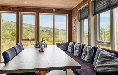 a living room with a table and a couch and windows at Cozy Home In Hovden I Setesdal - With Jacuzzi in Hovden