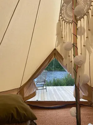 a tent with a wooden deck and a chair at River Glamping - Jordet, Trysil in Trysil