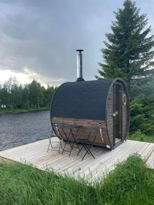 a circular structure sitting on a dock next to a river at River Glamping - Jordet, Trysil in Trysil