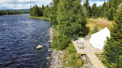 a dock on a river with a boat on it at River Glamping - Jordet, Trysil in Trysil