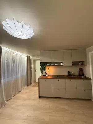 a kitchen with white cabinets and a chandelier at New Modern Apartment Near Tram Fantoft in Bergen