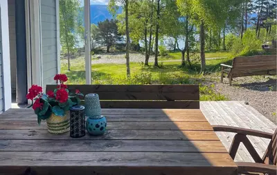 a wooden table with flowers and vases on a porch at 2 Bedroom Awesome Home In Lavik in Lavik