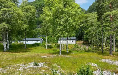 a group of houses in a field with trees at 2 Bedroom Awesome Home In Lavik in Lavik