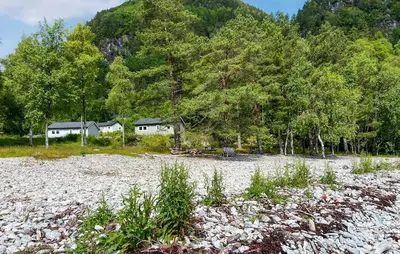 a gravel field with trees and a house in the background at 2 Bedroom Awesome Home In Lavik in Lavik