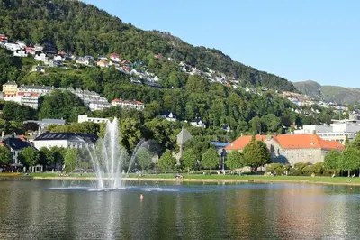 a fountain in a lake in front of a town at Cozy Gem in the Heart Of Bergen in Bergen