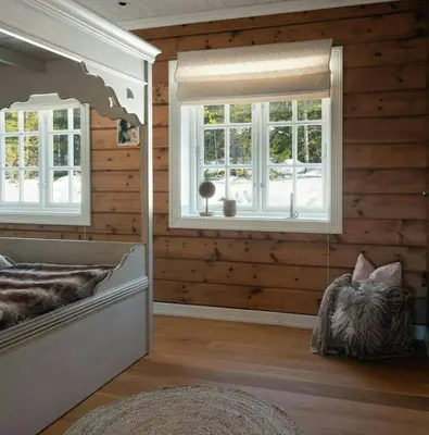 a bedroom with wooden walls and a bed with windows at Spacious Family Cabin At Nesfjellet With Views in Nesbyen