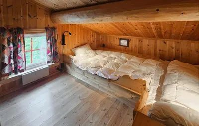 a large bed in a wooden room with a window at Cozy Home In Hemsedal With Sauna in Hemsedal