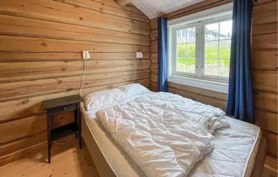 a bed in a wooden room with a window at Cozy Home In Sjusjøen With Wifi in Sjusjøen