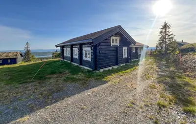 a small house on a hill with the sun in the sky at Cozy Home In Sjusjøen With Wifi in Sjusjøen