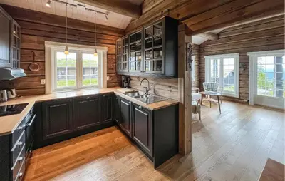 a kitchen with black cabinets and wooden walls at Cozy Home In Sjusjøen With Wifi in Sjusjøen