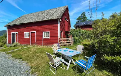 a table and chairs in front of a red barn at Nice Home In Eikelandsosen With Wifi in Eikelandsosen