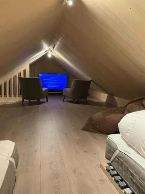 a room with two chairs and a tv in a attic at Modern Cabin Near Auersvatn And Ski Trails in Hovden
