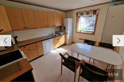 a kitchen with a table and a white refrigerator at Rom i bofelleskap in Sogndal