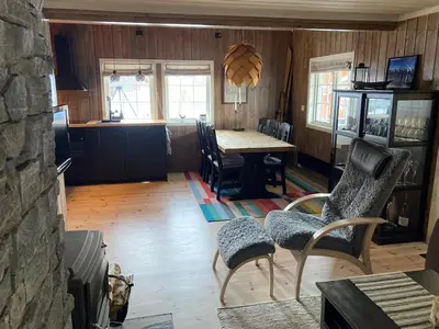 a living room with a table and chairs and a kitchen at Hovden Fjellpark 71 in Hovden