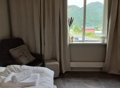 a bedroom with a bed and a chair and a window at Nesvika 5 bedroom holiday home, only 25 min from Bergen in Bergen