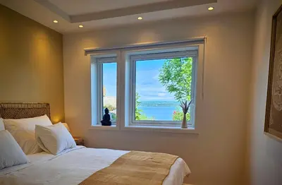 a bedroom with a bed and a large window at Helgøya Hideaway