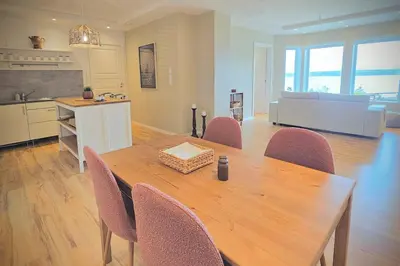 a kitchen and dining room with a wooden table and chairs at Helgøya Hideaway