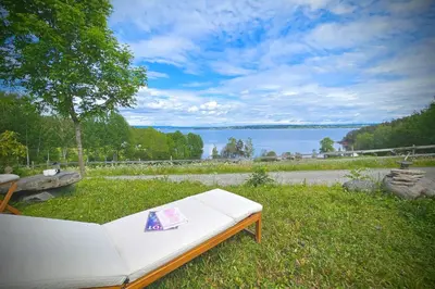 a white couch sitting in the grass next to a lake at Helgøya Hideaway