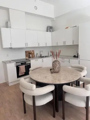 a kitchen with a table and chairs and a kitchen with white cabinets at ingen in Bergen