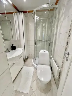 a white bathroom with a toilet and a shower at Floien City Apartment -Free parking in Bergen
