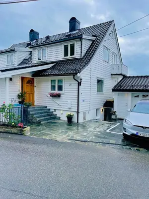 a white house with a car parked in front of it at Floien City Apartment -Free parking in Bergen