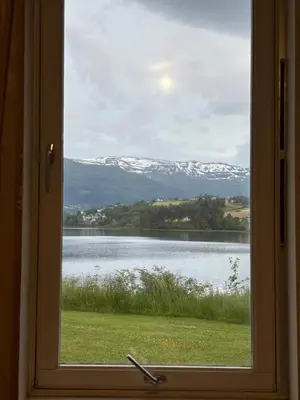 a window with a view of a lake and snow covered mountains at Unique and romantic Lakeside Experience in Vossevangen