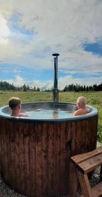 two men sitting in a hot tub in a field at Luxury Mountain Cabin Modern and Stylish in Uppheim
