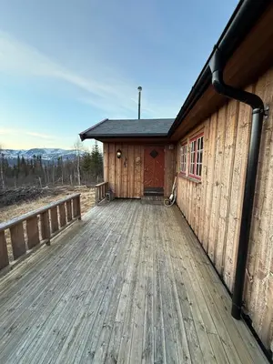 a building with a wooden deck with a red door at Spacious mountain cabin in Valdres with 3 bedrooms in Vevle