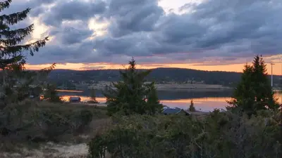 a sunset over a body of water with trees at Nordseter Sjusjøen fiske, jakt, tur og ski in Lillehammer