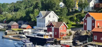 a large boat docked in a marina next to houses at Waterfront Villa Boat Included, Near Bergen in Lindås