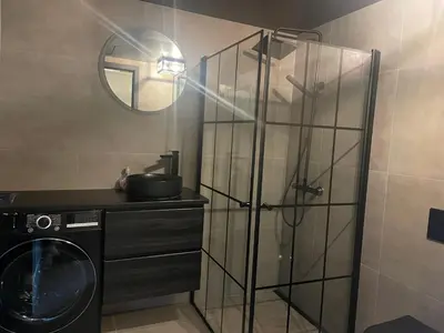 a bathroom with a washing machine and a glass shower at Modern 4-Bedroom Apartment in Beitostøl