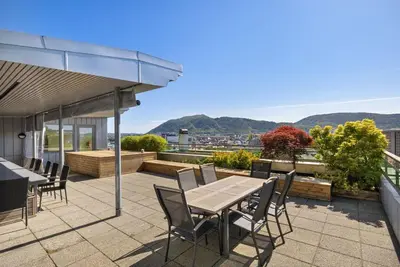 a patio with a table and chairs on a roof at Central Bergen apt w Balcony in Bergen