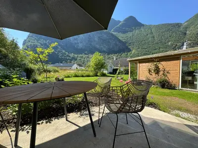 a table and chairs with an umbrella on a patio at Flåm Tinyhouse with a Waterfall View in Flåm