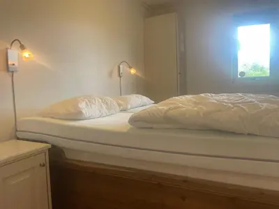 a bed with white sheets and pillows in a bedroom at Sentral, Hc-Friendly Apartment in Beitostøl