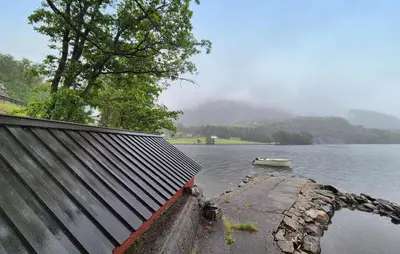 a boat in the water next to a house at Nice Home In Aksdal With House Sea View in Aksdal