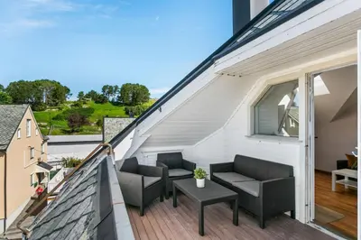 a balcony with chairs and a table on a building at Large apartment with 5 bedrooms, 2 bathrooms and roof terrace in Ålesund