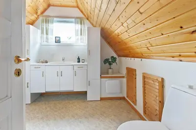 a bathroom with white cabinets and a wooden ceiling at City apartment with 4 bedrooms & private terrace in Ålesund