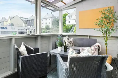 an outdoor patio with a table and chairs and windows at City apartment with 4 bedrooms & private terrace in Ålesund