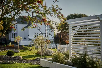 a white garden with a white fence and a white house at Stangeland Gard in Austevoll