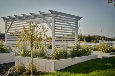 a white pergola with plants in a garden at Stangeland Gard in Austevoll
