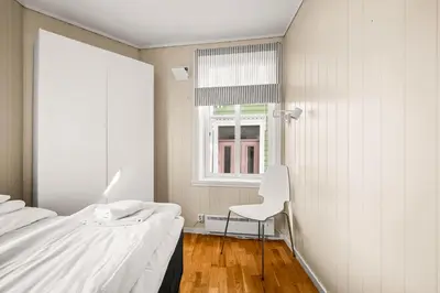 a bedroom with a white bed and a white chair at Bergen Charm - Right in the City Center! in Bergen