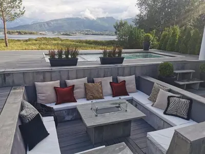 a patio with a bench with pillows and a pool at Exclusive seafront villa in Ålesund
