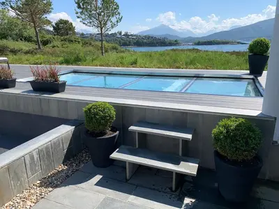 a swimming pool with a bench and some plants at Exclusive seafront villa in Ålesund